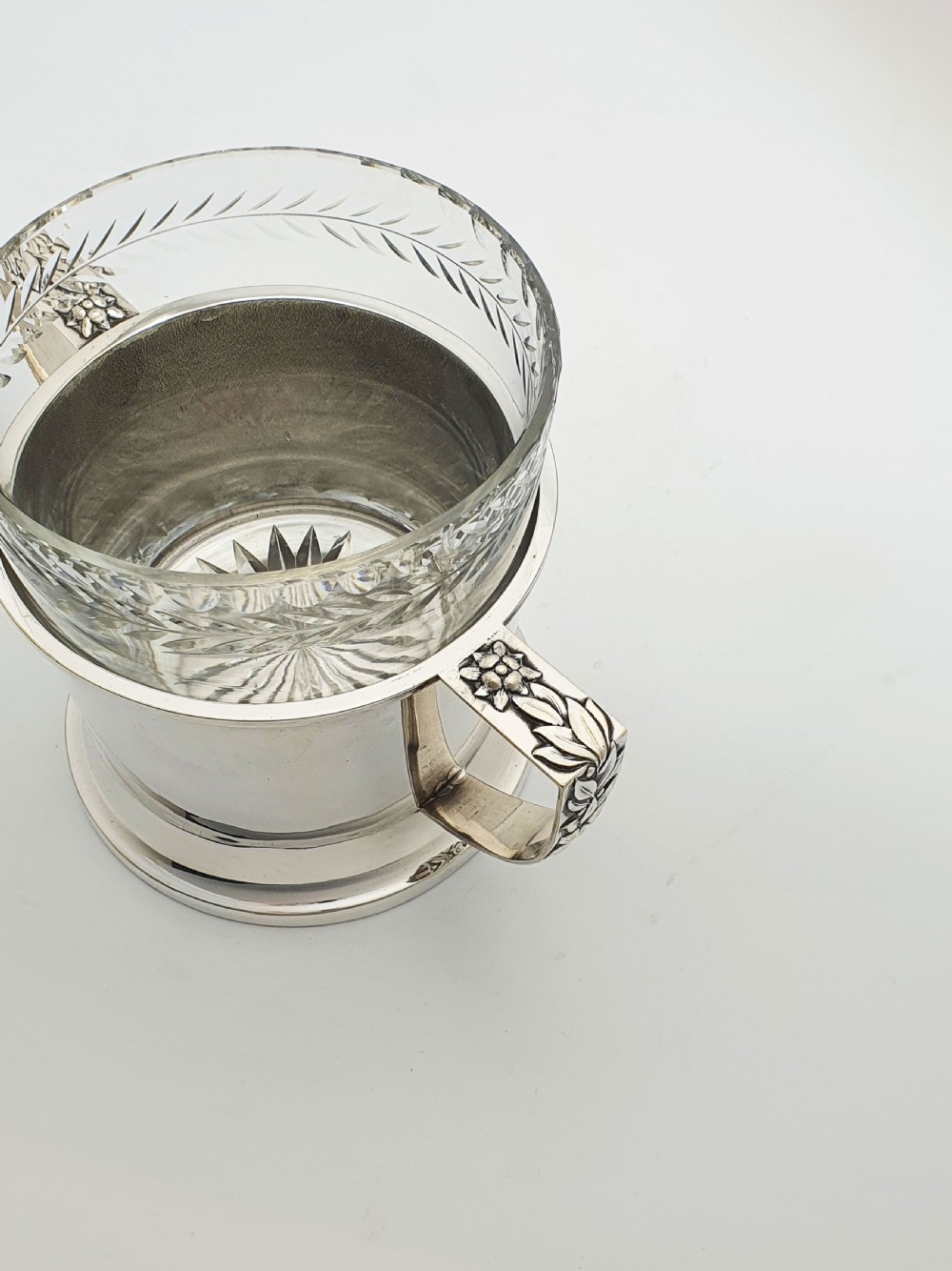 An Art Deco silver-plated ice bucket featuring twin handles, a removable cut-glass liner with a leaf pattern, and matching ice tongs. View VI
