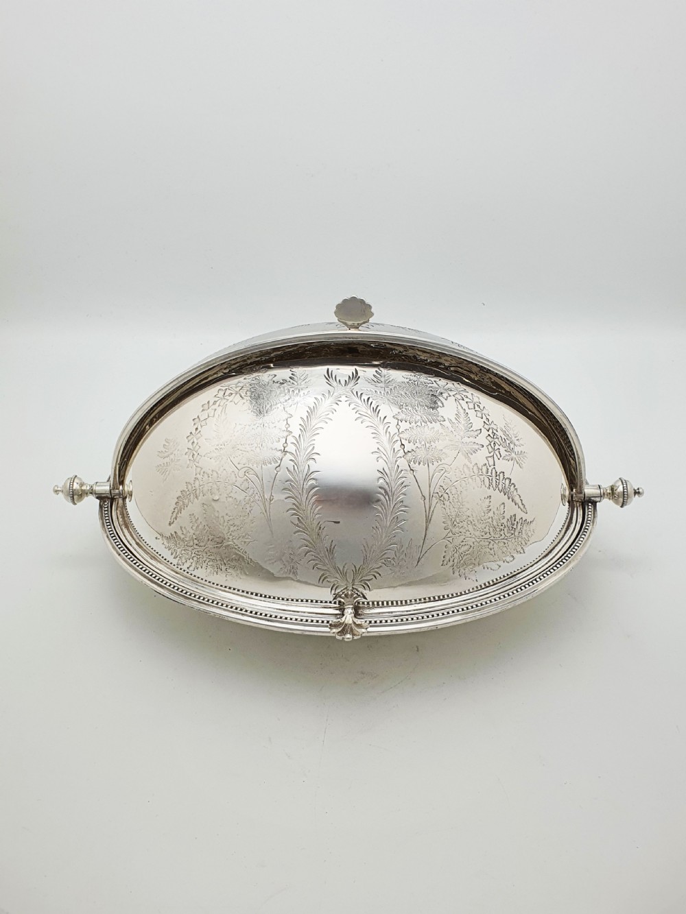A late Victorian oval silver-plated rollover dish featuring bright-cut botanical engravings, a beaded rim, and side pivot handles. View II