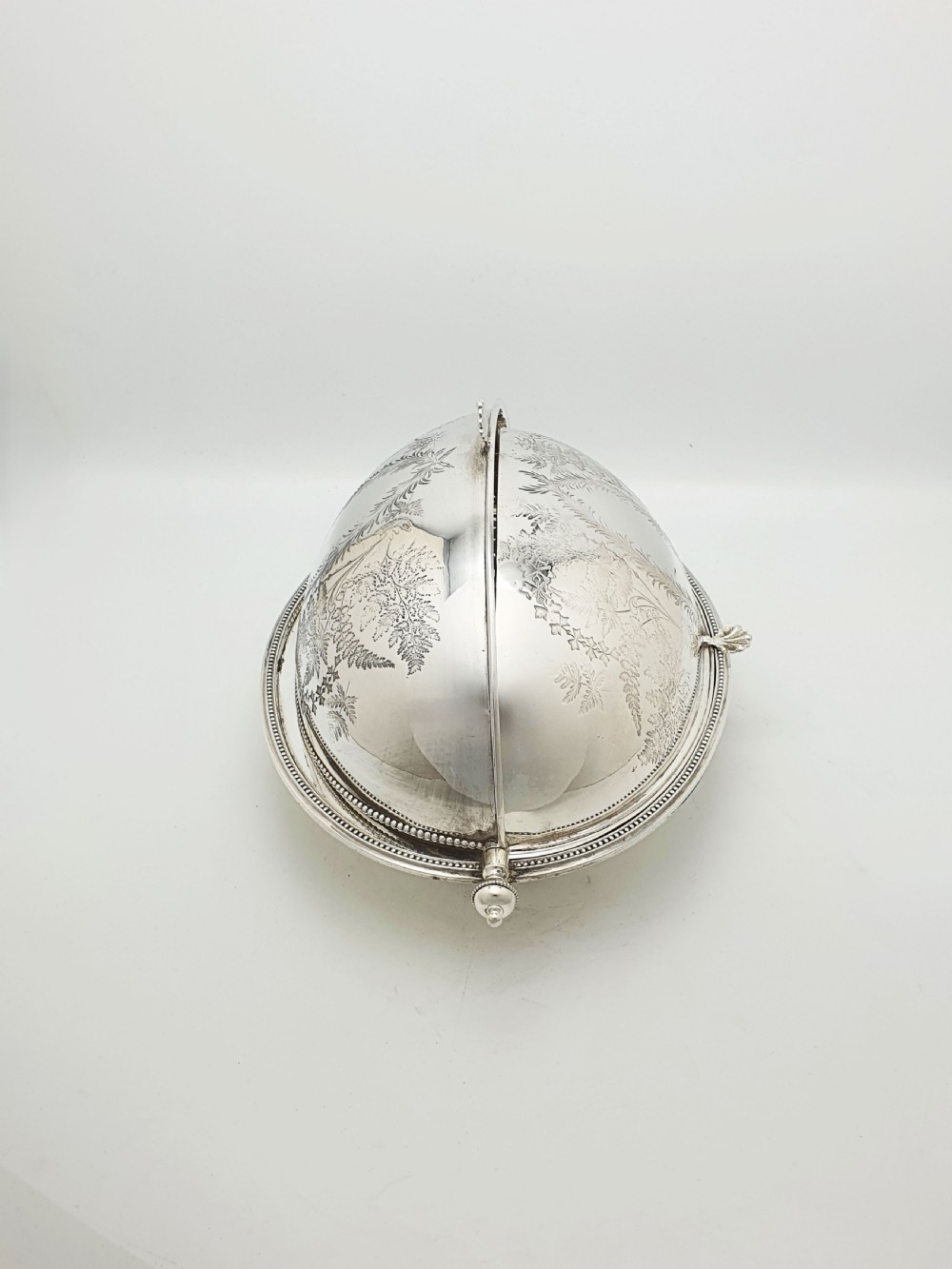 A late Victorian oval silver-plated rollover dish featuring bright-cut botanical engravings, a beaded rim, and side pivot handles. View III