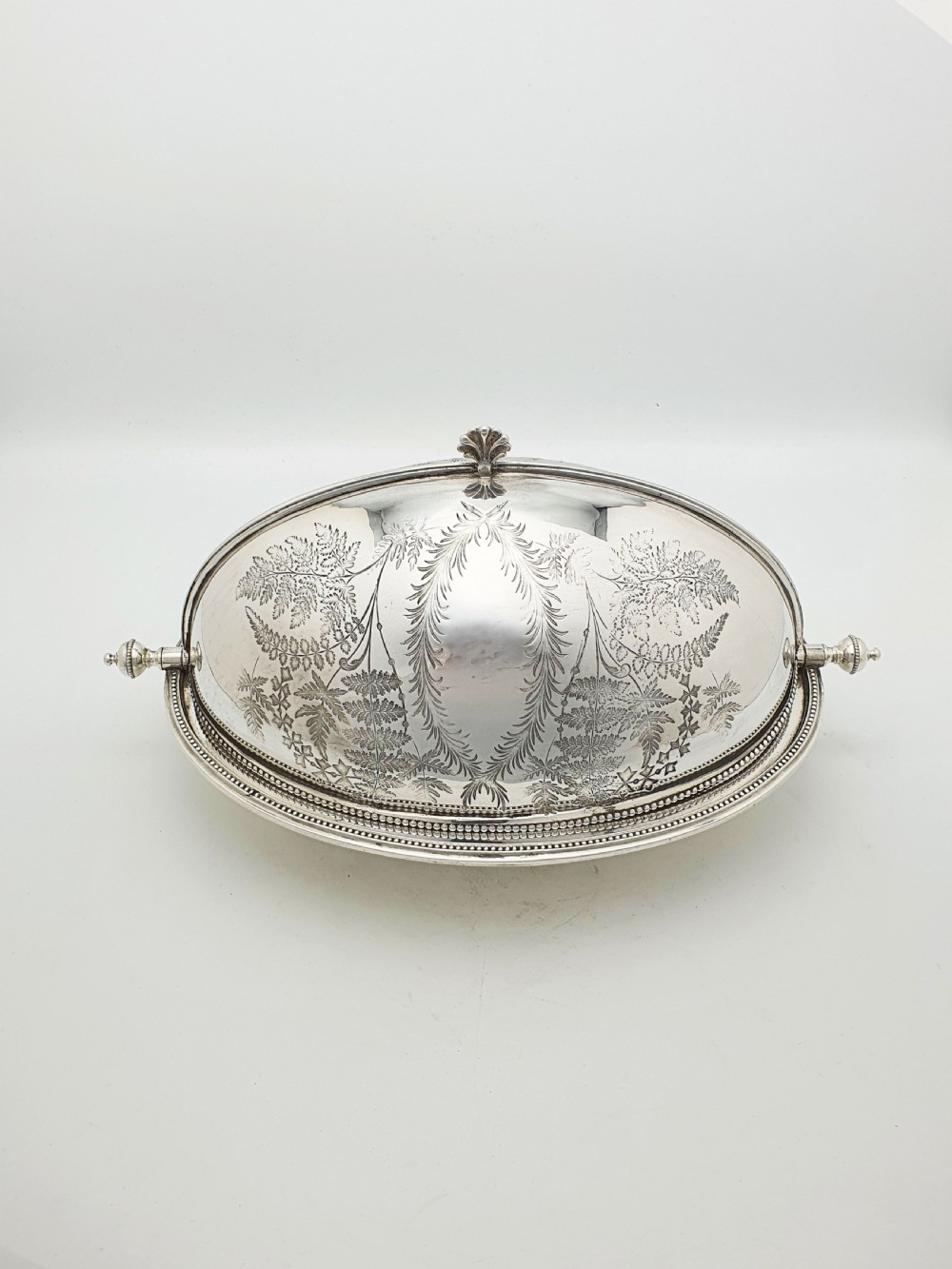 A late Victorian oval silver-plated rollover dish featuring bright-cut botanical engravings, a beaded rim, and side pivot handles. View IV