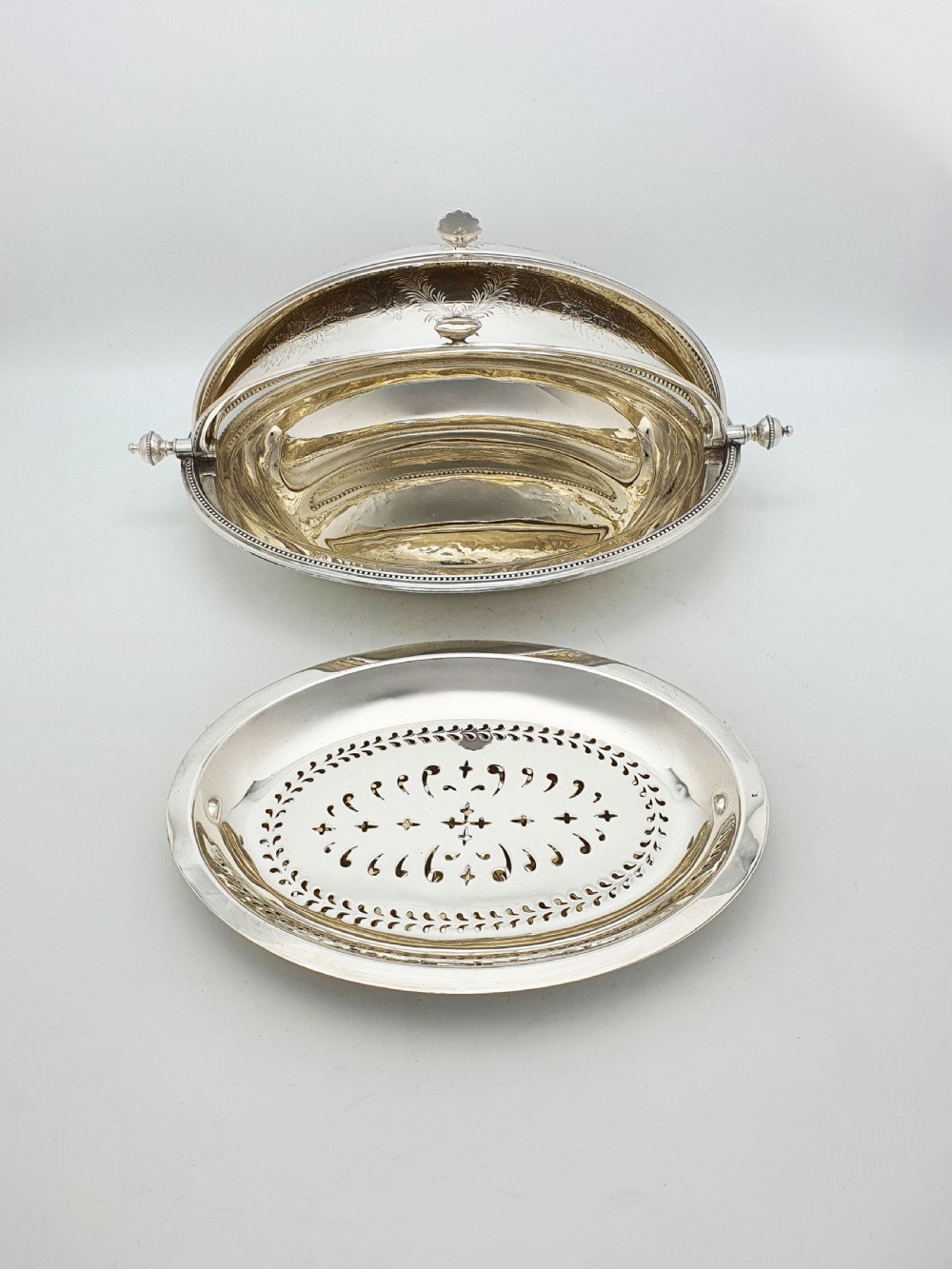 A late Victorian oval silver-plated rollover dish featuring bright-cut botanical engravings, a beaded rim, and side pivot handles. View VII