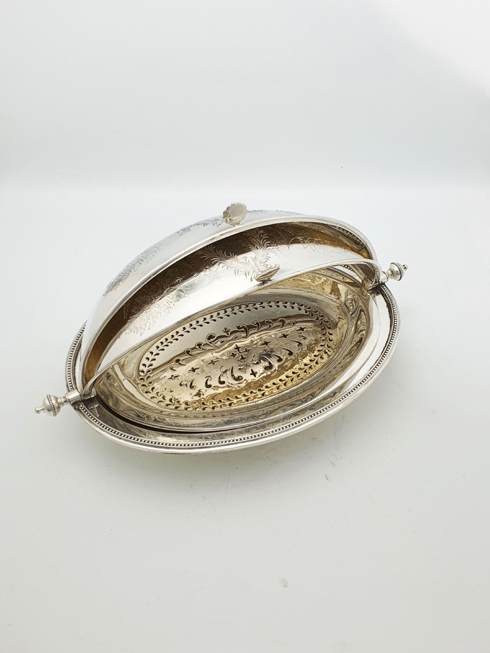 A late Victorian oval silver-plated rollover dish featuring bright-cut botanical engravings, a beaded rim, and side pivot handles. View XII