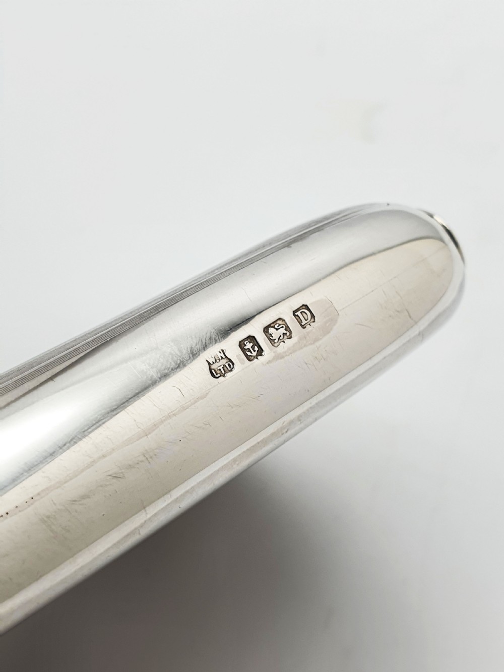 An Art Deco sterling silver hip flask featuring a curved rectangular body decorated with engine-turned linear engraving and a captive bayonet cap. View VIII