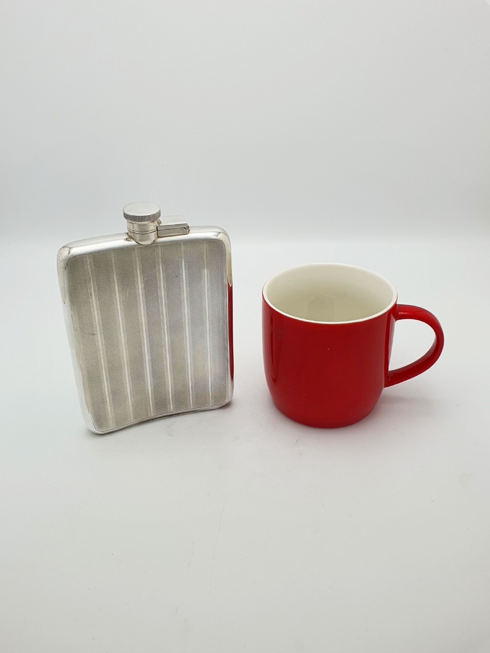 An Art Deco sterling silver hip flask featuring a curved rectangular body decorated with engine-turned linear engraving and a captive bayonet cap. View XI