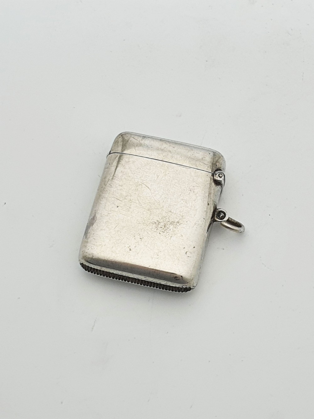 A rectangular sterling silver vesta case featuring a hinged top, side suspension ring, bottom striker, and a colourful heraldic enamel crest on the front. View III