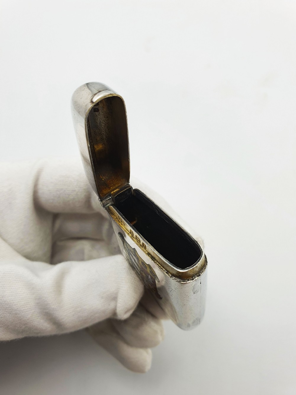 A rectangular sterling silver vesta case featuring a hinged top, side suspension ring, bottom striker, and a colourful heraldic enamel crest on the front. View V