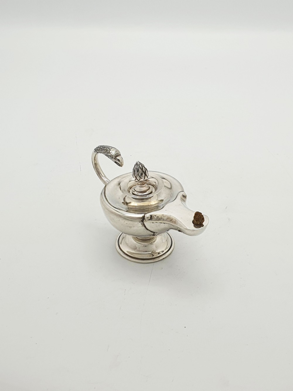 A sterling silver table lighter crafted in the shape of a classical Roman oil lamp with a serpent-shaped handle and pedestal foot.