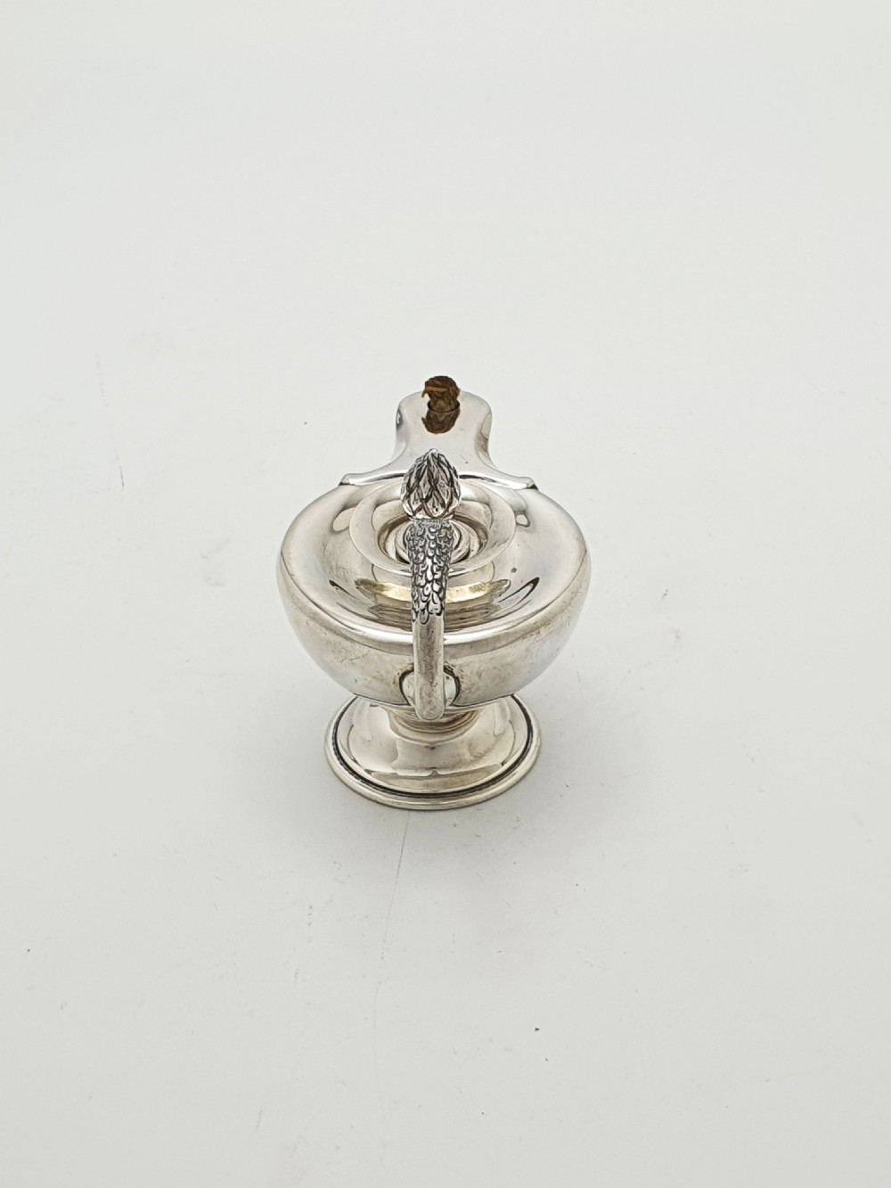 A sterling silver table lighter crafted in the shape of a classical Roman oil lamp with a serpent-shaped handle and pedestal foot. View VI