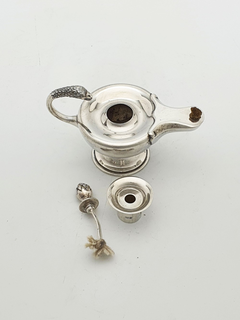 A sterling silver table lighter crafted in the shape of a classical Roman oil lamp with a serpent-shaped handle and pedestal foot. View VII