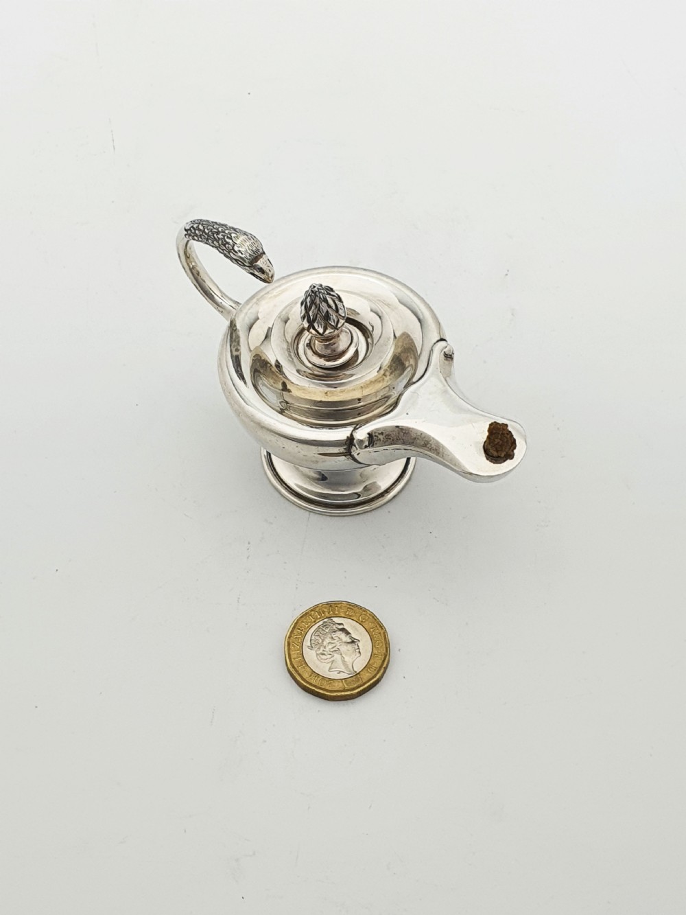 A sterling silver table lighter crafted in the shape of a classical Roman oil lamp with a serpent-shaped handle and pedestal foot. View X