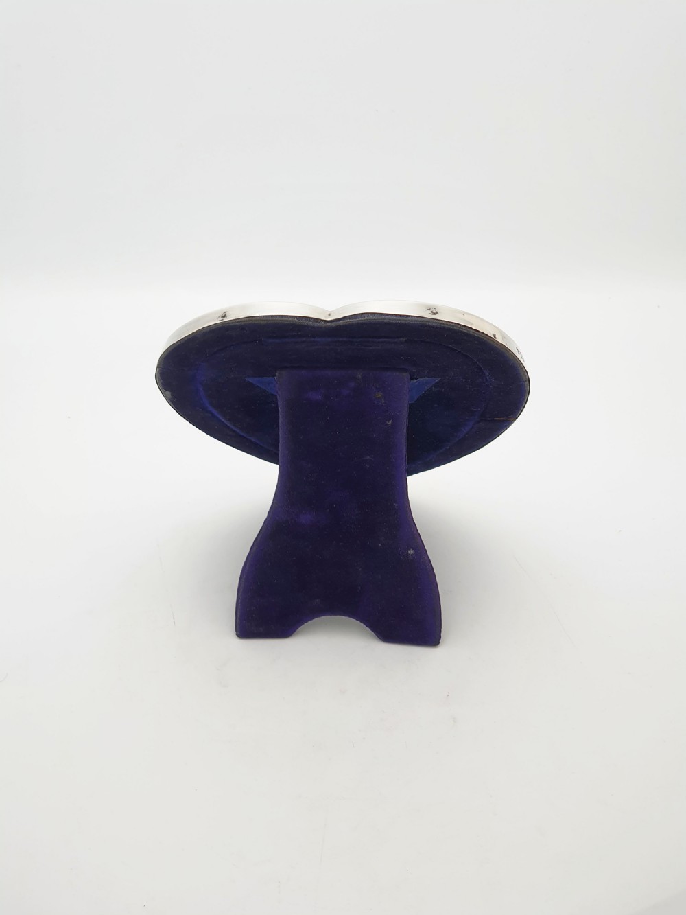 A heart-shaped Edwardian sterling silver picture frame with a smooth polished finish and dark blue display interior. View III