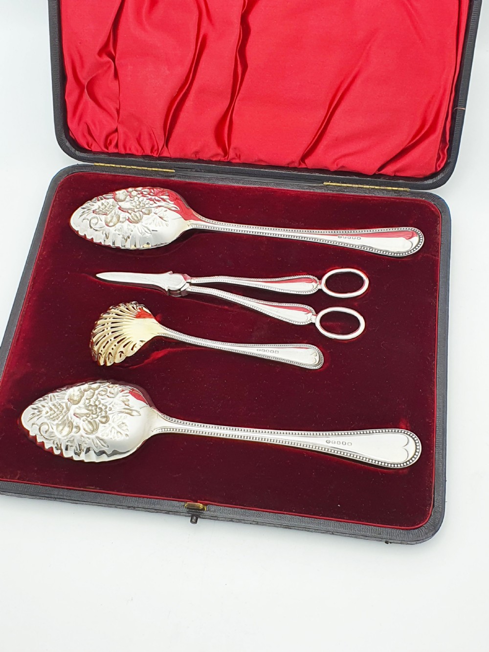 A Victorian silver-plated fruit serving set with embossed gilt bowls and grape shears, displayed inside a red velvet-lined presentation box. View V