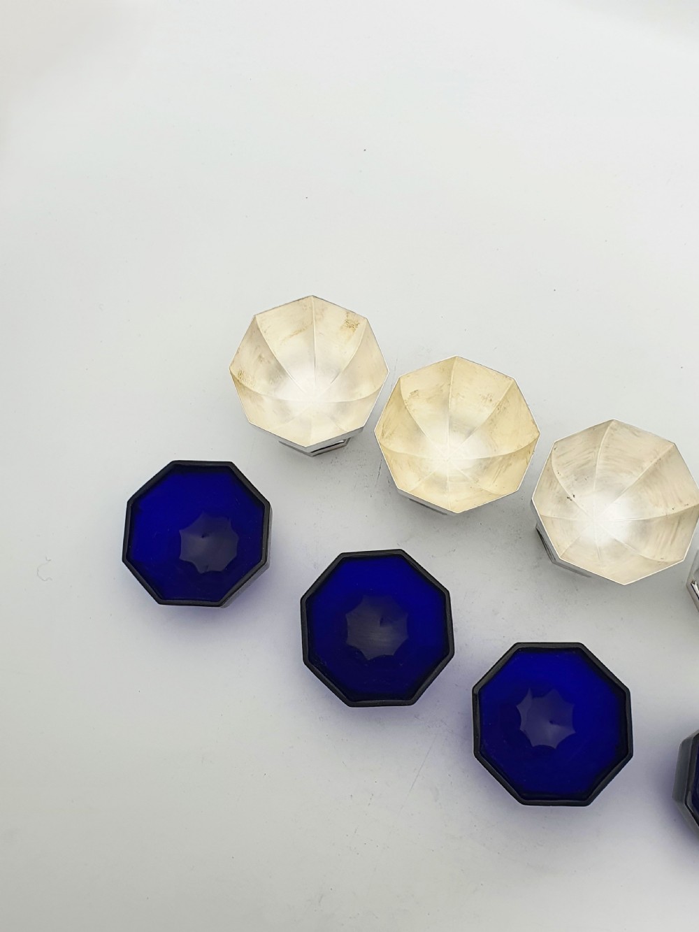 A set of four octagonal silver-plated salt cellars featuring dark cobalt blue glass liners on stepped pedestal bases. View VIII