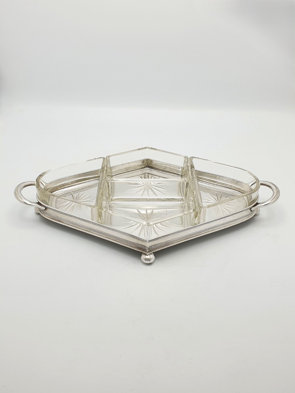 An Art Deco silver-plated tray featuring twin handles and ball feet, holding four fitted clear glass compartments with starburst cut patterns. View II