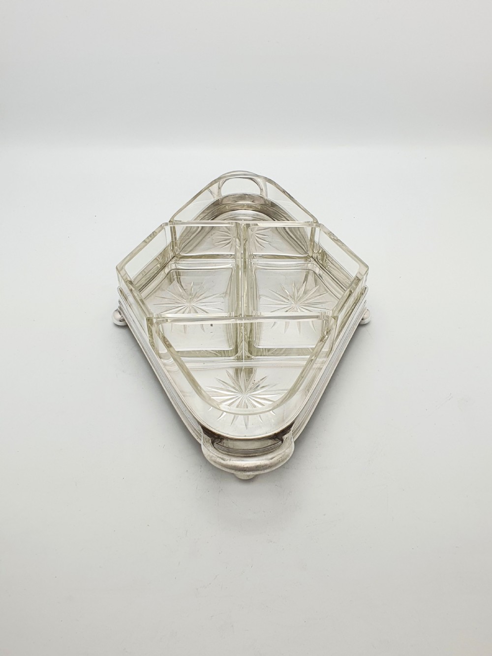 An Art Deco silver-plated tray featuring twin handles and ball feet, holding four fitted clear glass compartments with starburst cut patterns. View III
