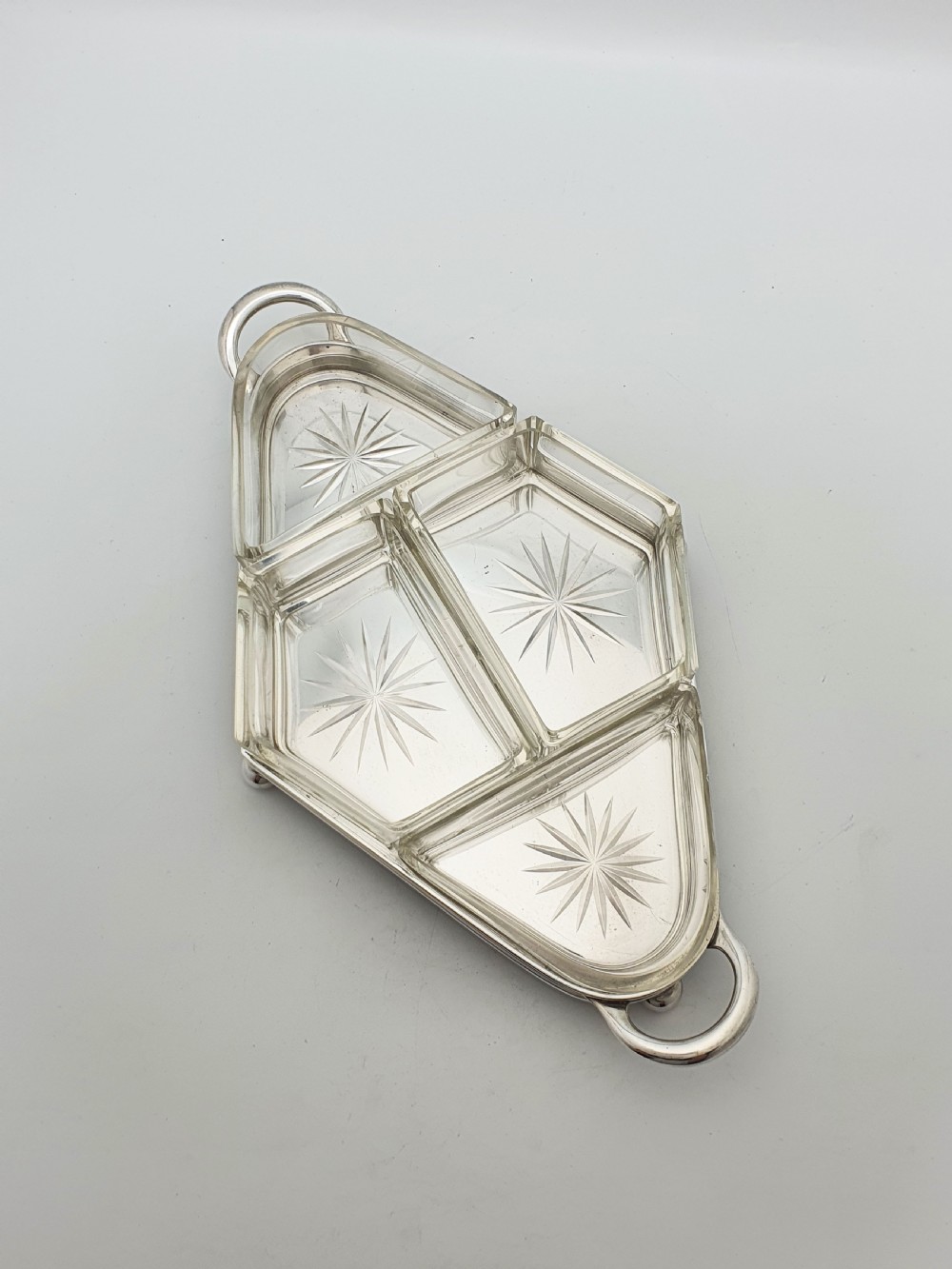 An Art Deco silver-plated tray featuring twin handles and ball feet, holding four fitted clear glass compartments with starburst cut patterns. View VI