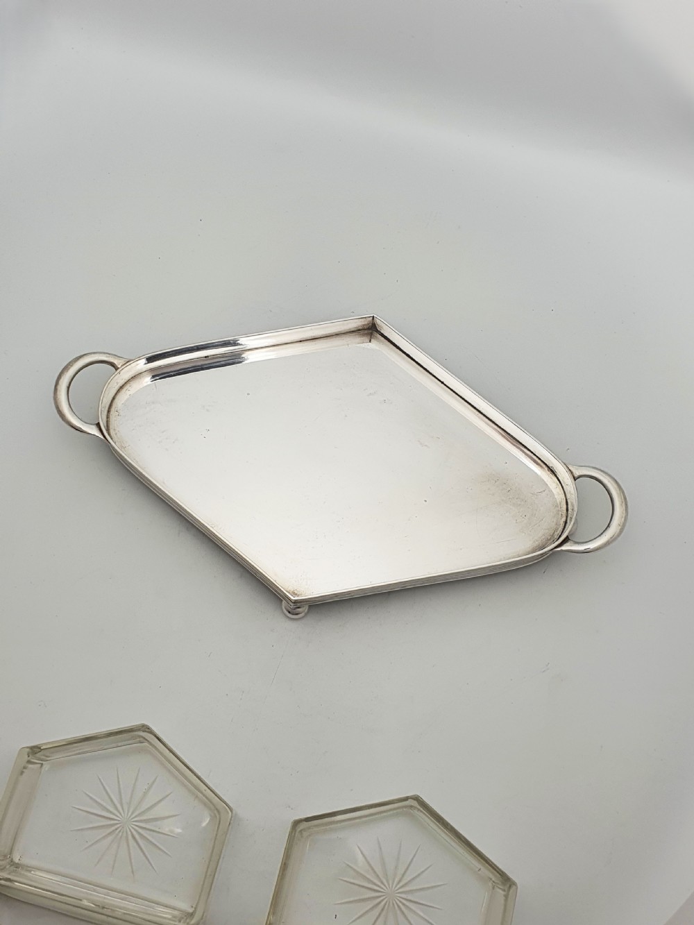 An Art Deco silver-plated tray featuring twin handles and ball feet, holding four fitted clear glass compartments with starburst cut patterns. View VII