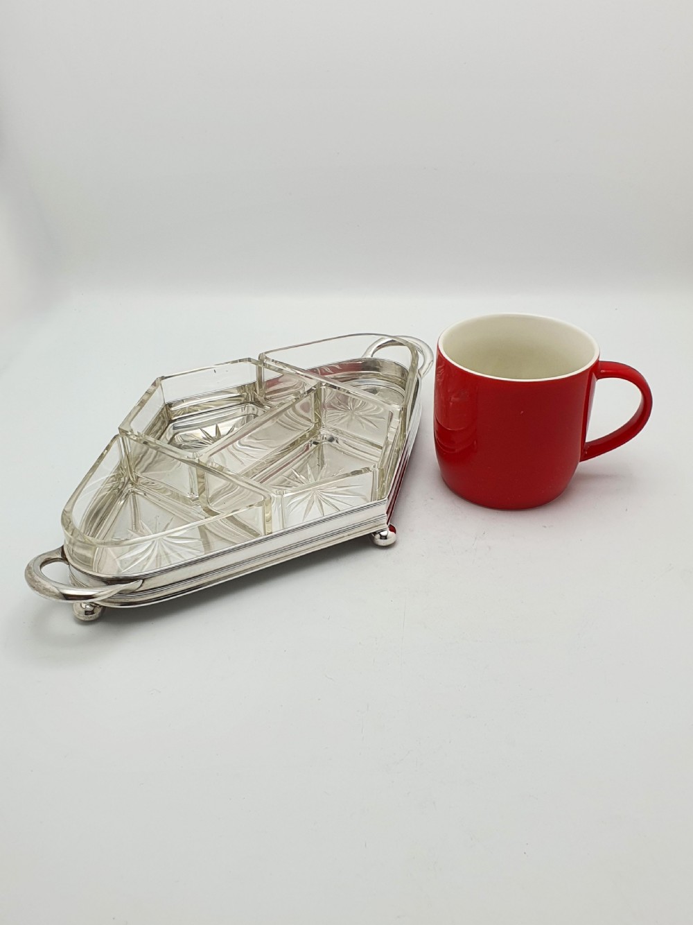 An Art Deco silver-plated tray featuring twin handles and ball feet, holding four fitted clear glass compartments with starburst cut patterns. View X