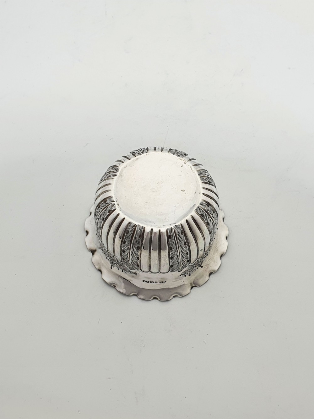A small Late Victorian sterling silver bowl featuring fluted leaf decoration, floral engraving, a crimped rim, and a gilded interior. View V