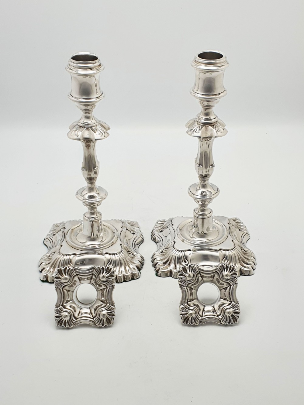 Pair of polished silver-plated Rococo Revival candlesticks with shell motifs and knopped stems on a plain background. View VI