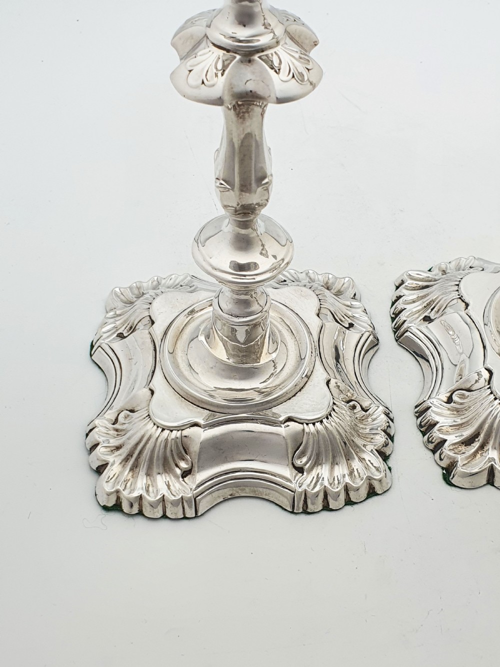 Pair of polished silver-plated Rococo Revival candlesticks with shell motifs and knopped stems on a plain background. View VII