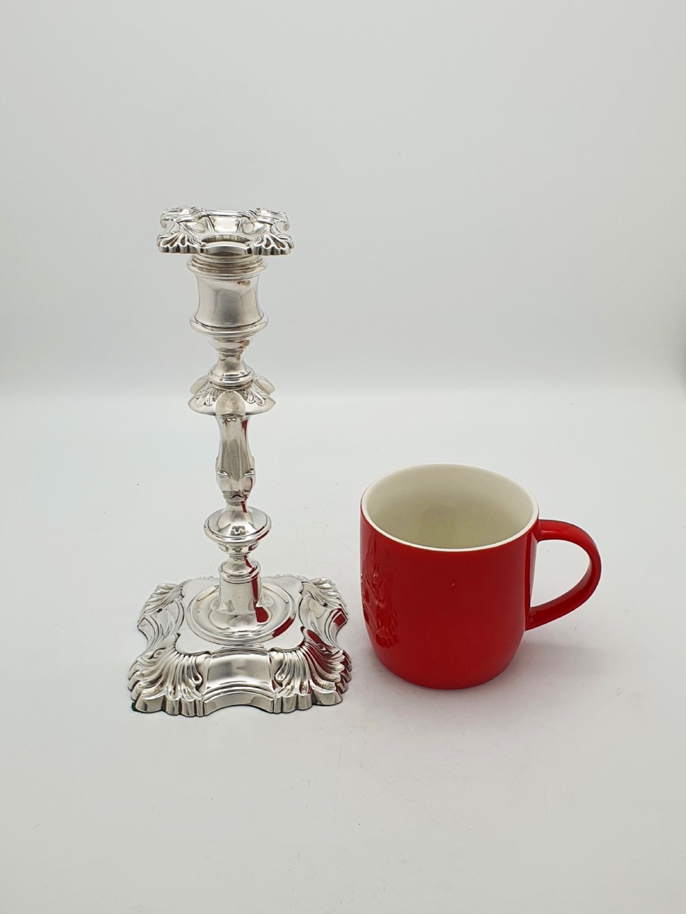 Pair of polished silver-plated Rococo Revival candlesticks with shell motifs and knopped stems on a plain background. View VIII