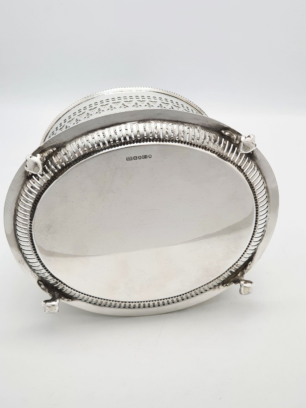 An Edwardian silver plated biscuit barrel featuring pierced scrollwork spelling out the word biscuits, a matching tray base, and a hinged lid with a decorative finial. View X