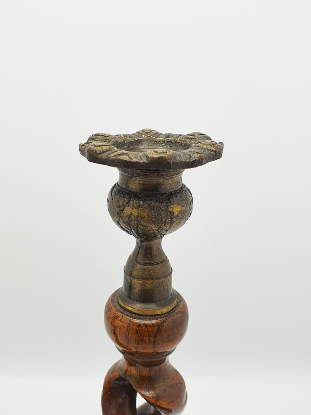 A pair of dark oak candlesticks featuring open barley twist stems and brass sconces atop round dished bases. View V