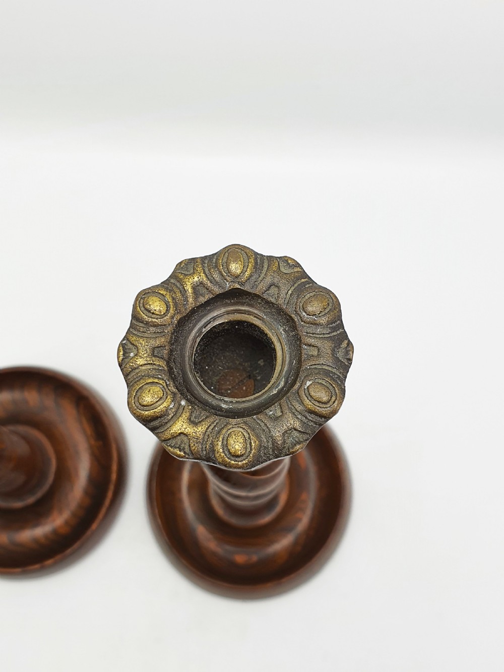 A pair of dark oak candlesticks featuring open barley twist stems and brass sconces atop round dished bases. View VII
