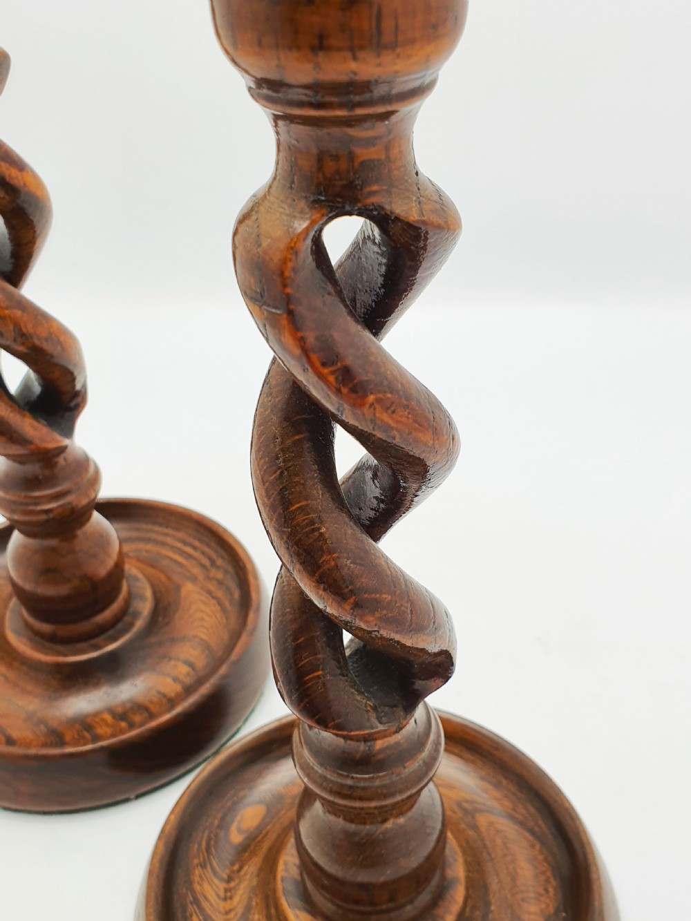 A pair of dark oak candlesticks featuring open barley twist stems and brass sconces atop round dished bases. View X