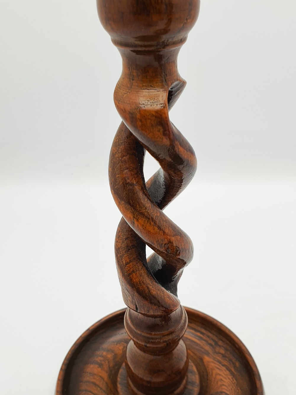 A pair of dark oak candlesticks featuring open barley twist stems and brass sconces atop round dished bases. View XI