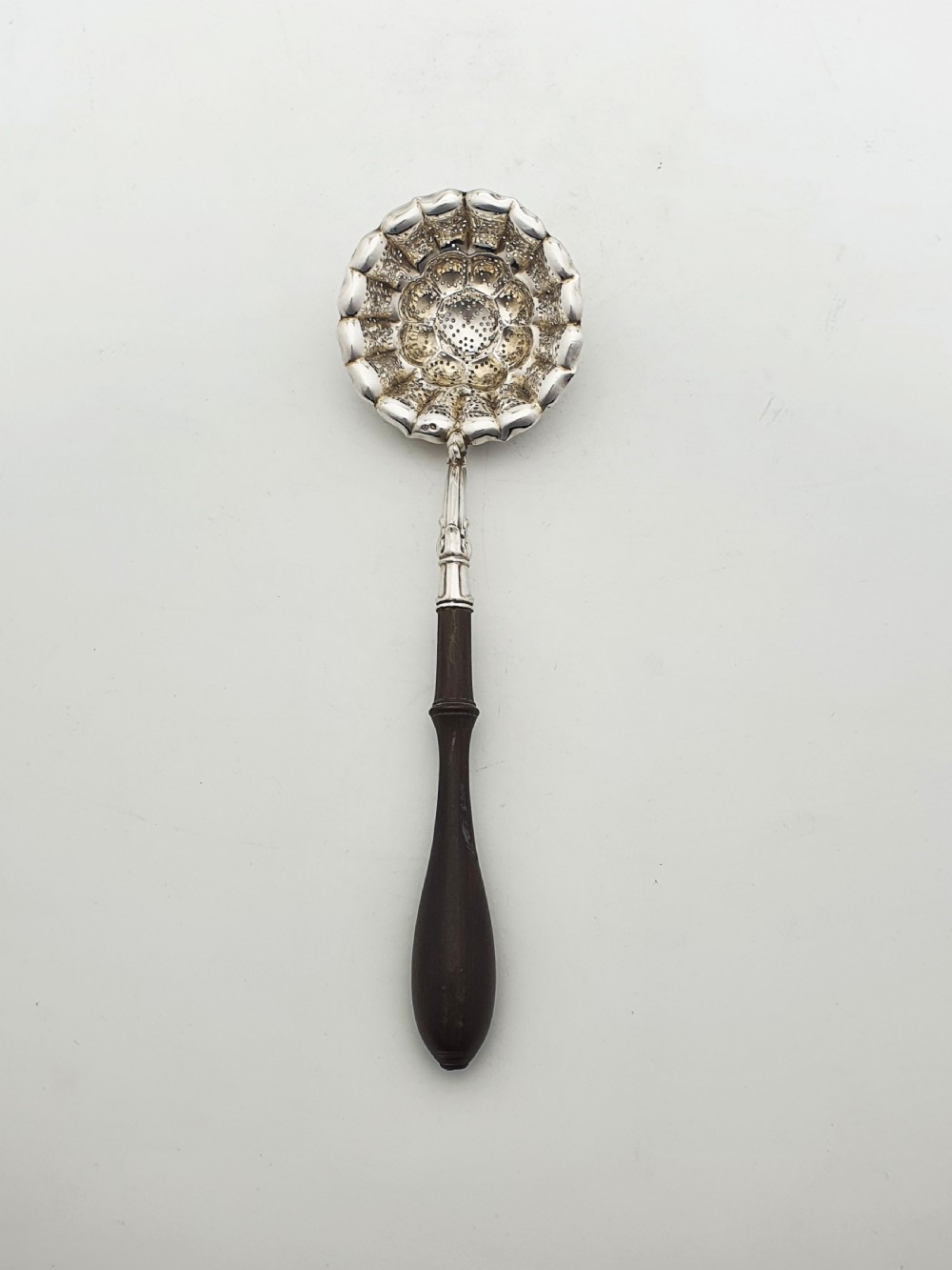 A late nineteenth-century Continental silver tea strainer featuring a fluted pierced bowl attached to a dark turned wooden handle. View III