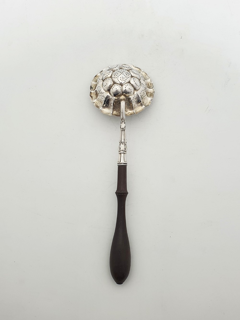 A late nineteenth-century Continental silver tea strainer featuring a fluted pierced bowl attached to a dark turned wooden handle. View IV