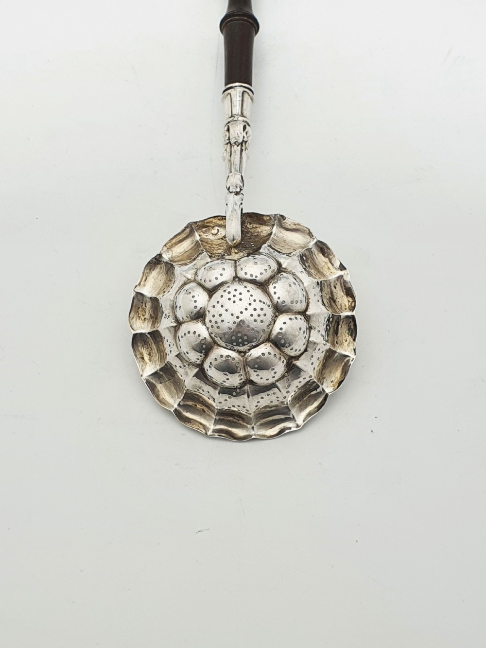 A late nineteenth-century Continental silver tea strainer featuring a fluted pierced bowl attached to a dark turned wooden handle. View V