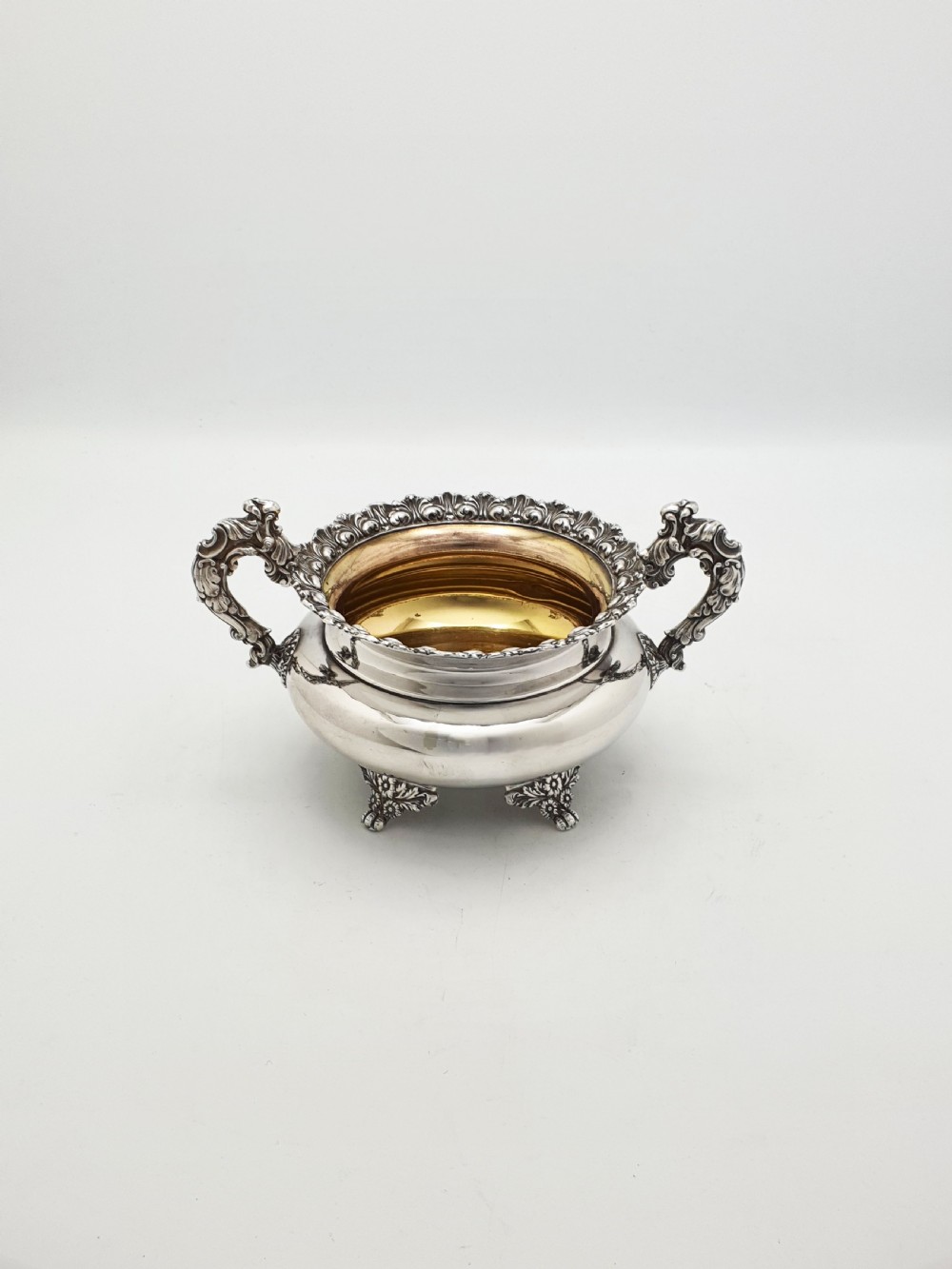 A Georgian silver-plated sugar bowl and matching cream jug with heavily carved scroll rims, double-scroll handles, and gilded interiors. View II