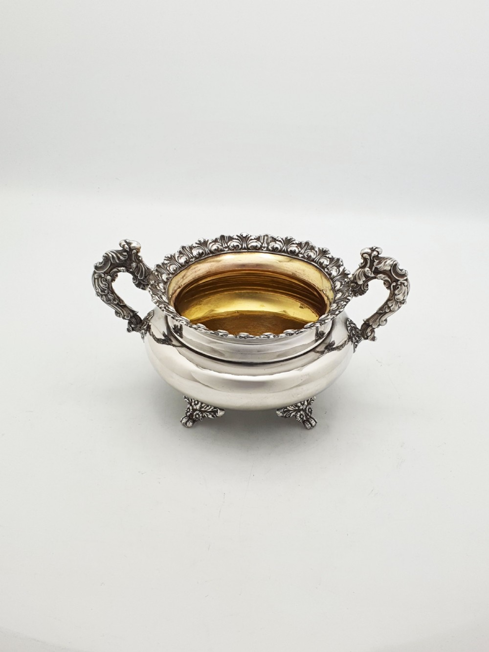 A Georgian silver-plated sugar bowl and matching cream jug with heavily carved scroll rims, double-scroll handles, and gilded interiors. View III