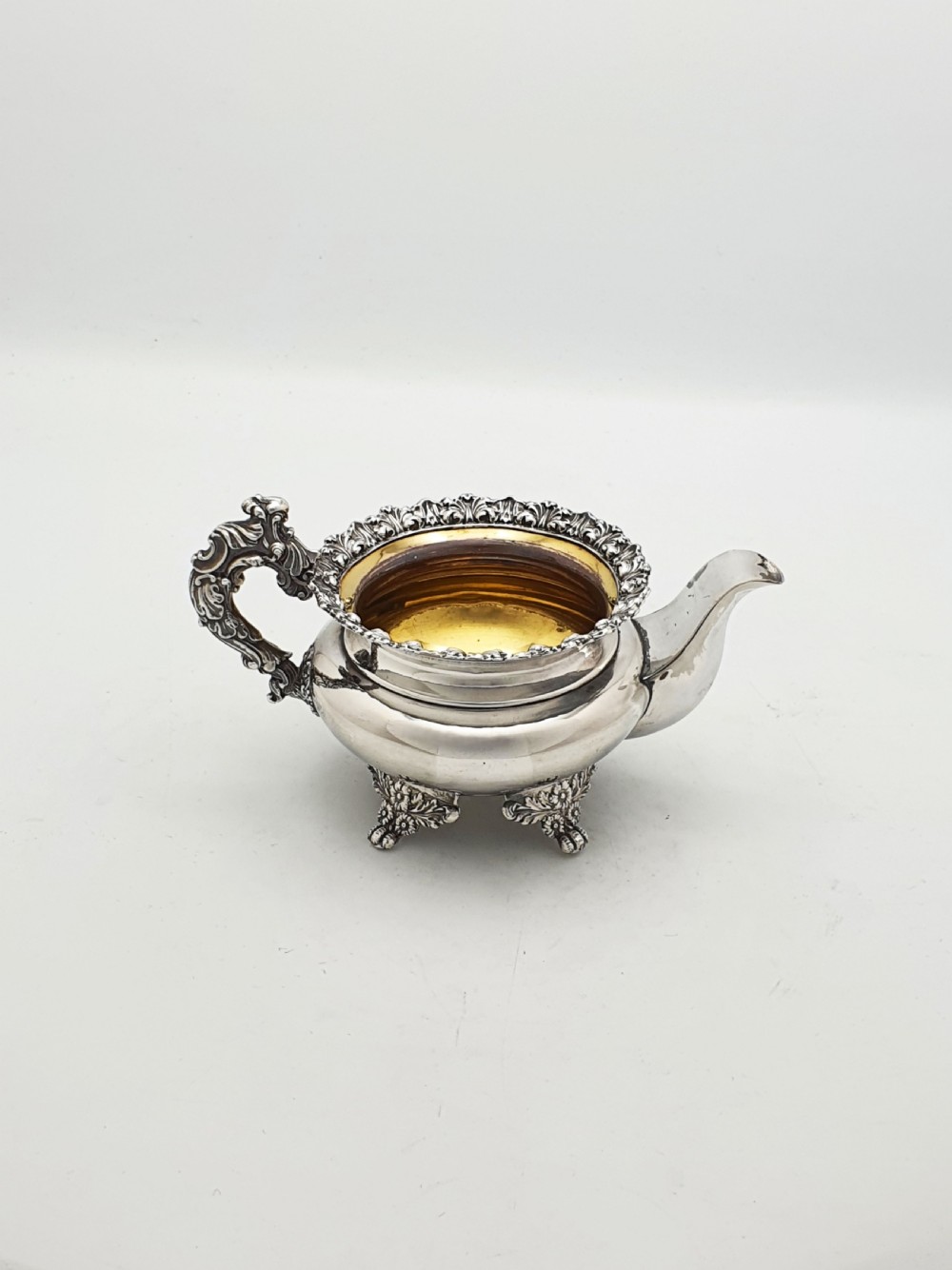 A Georgian silver-plated sugar bowl and matching cream jug with heavily carved scroll rims, double-scroll handles, and gilded interiors. View IV