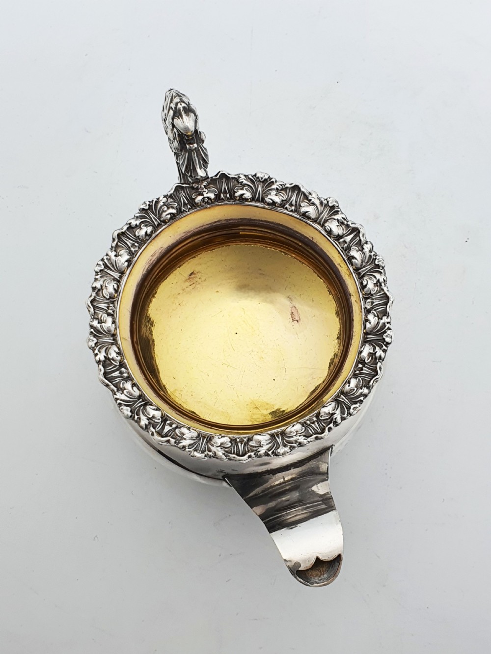 A Georgian silver-plated sugar bowl and matching cream jug with heavily carved scroll rims, double-scroll handles, and gilded interiors. View V