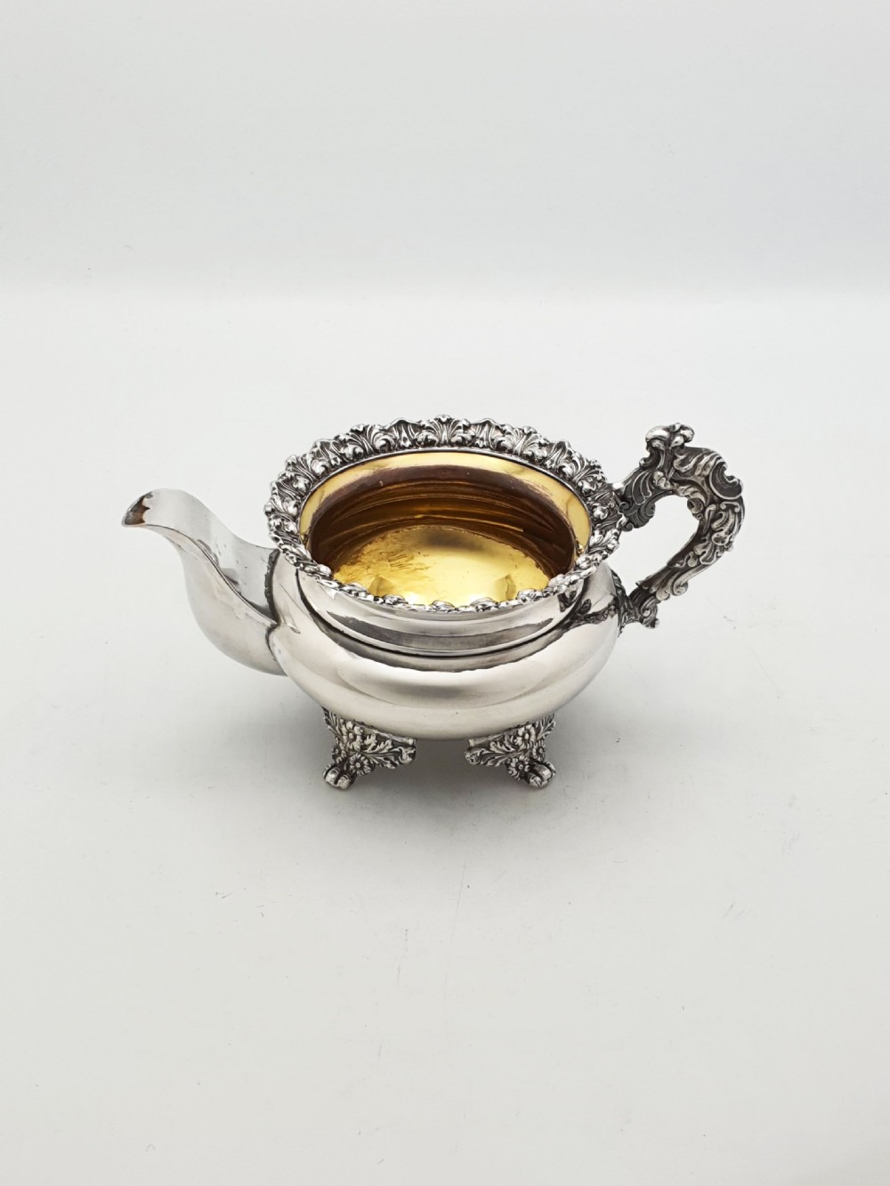 A Georgian silver-plated sugar bowl and matching cream jug with heavily carved scroll rims, double-scroll handles, and gilded interiors. View VI
