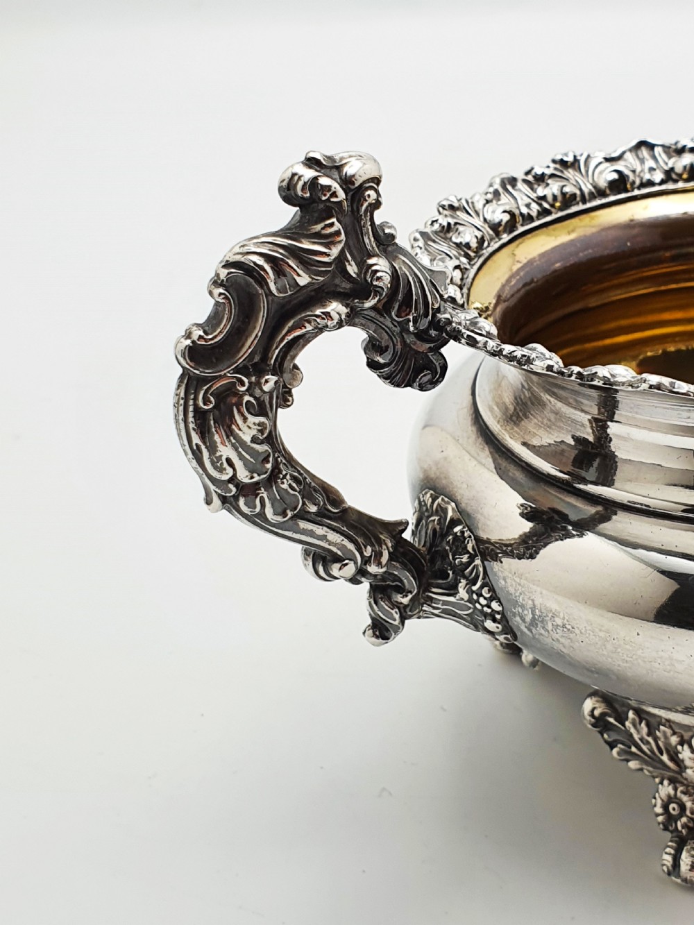 A Georgian silver-plated sugar bowl and matching cream jug with heavily carved scroll rims, double-scroll handles, and gilded interiors. View VII