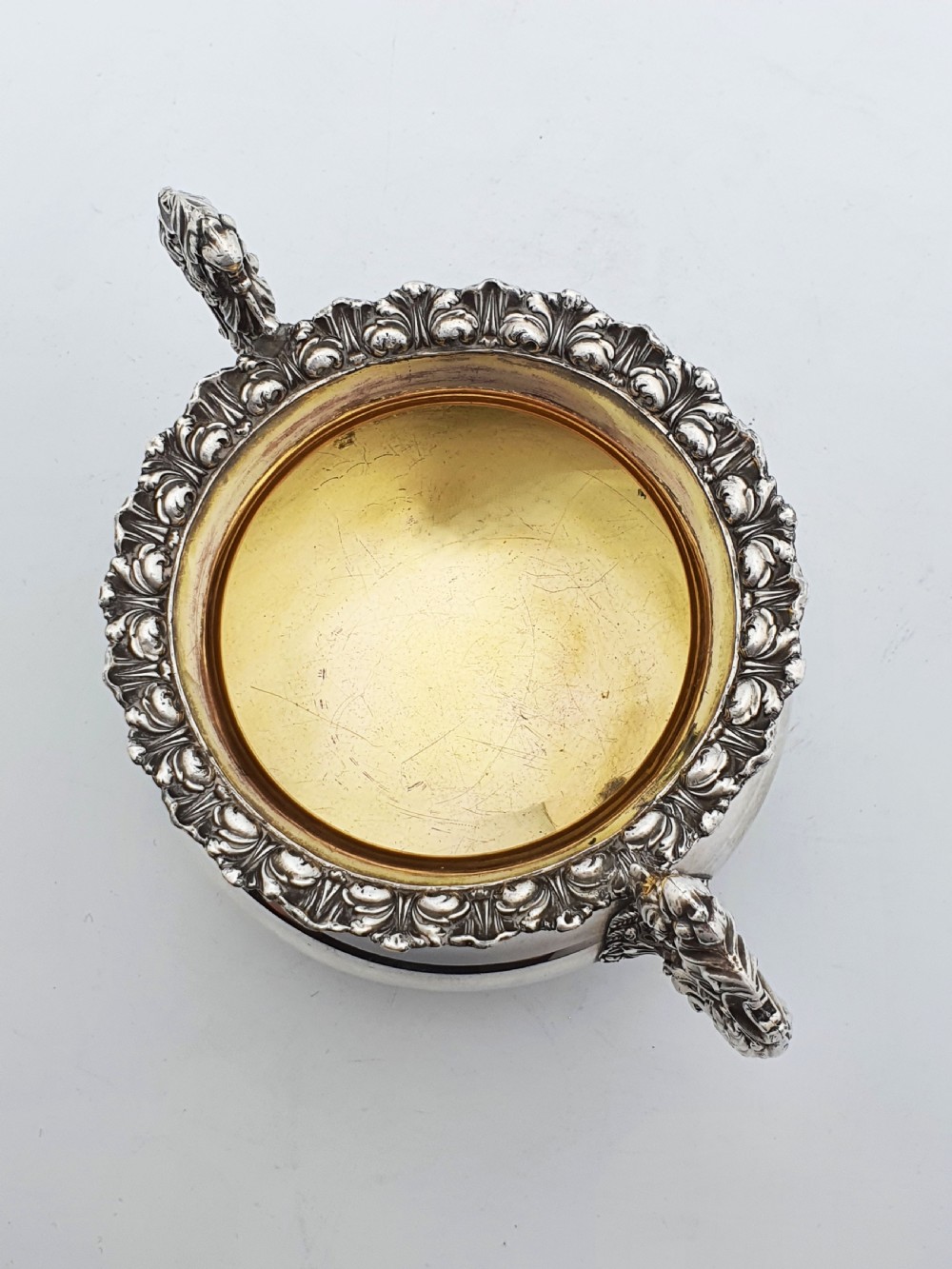 A Georgian silver-plated sugar bowl and matching cream jug with heavily carved scroll rims, double-scroll handles, and gilded interiors. View IX
