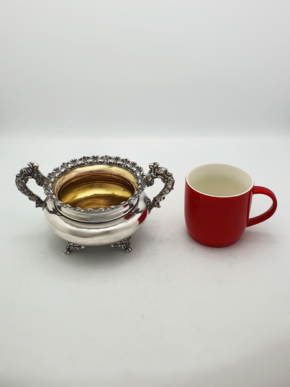 A Georgian silver-plated sugar bowl and matching cream jug with heavily carved scroll rims, double-scroll handles, and gilded interiors. View XII