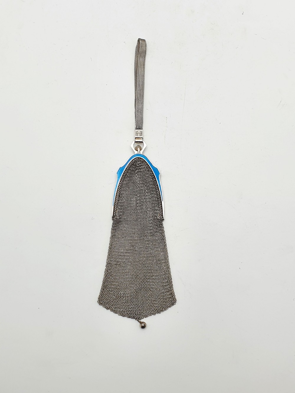An antique silver mesh purse featuring a blue guilloche enamel top frame, a woven silver strap, and a hanging metal drop. View II