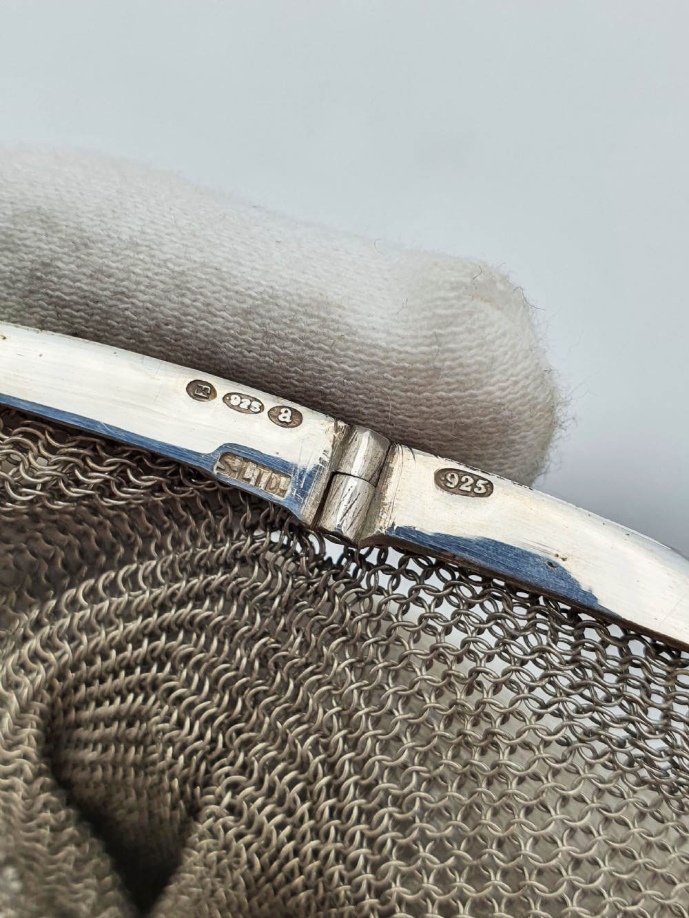 An antique silver mesh purse featuring a blue guilloche enamel top frame, a woven silver strap, and a hanging metal drop. View VII