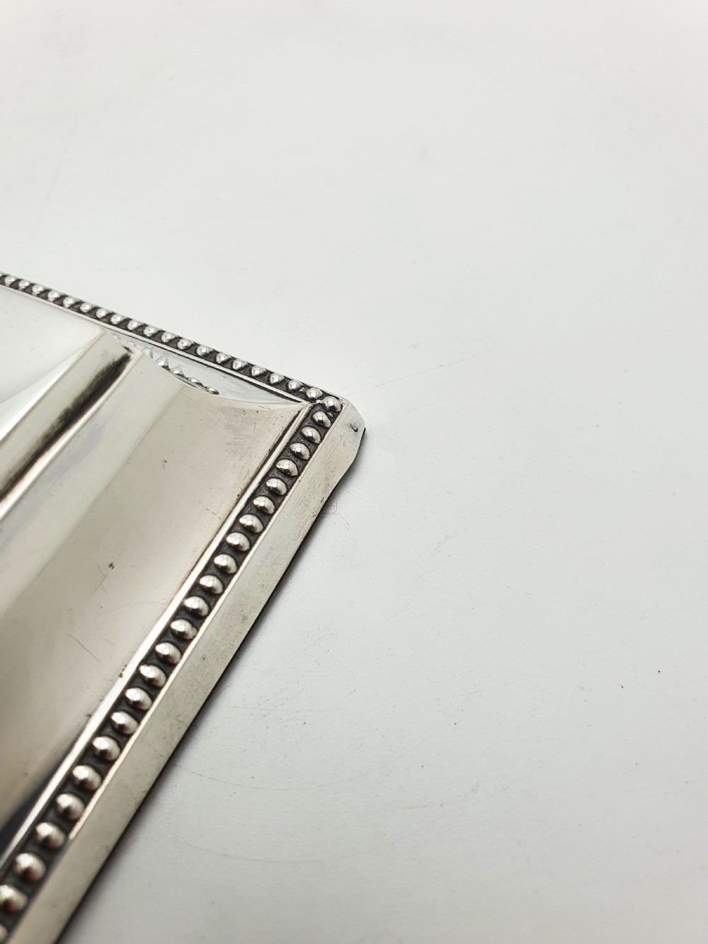 A late Victorian sterling silver receipt hook featuring a square stepped plinth base with beaded detail and a upright hooked stem. View IX