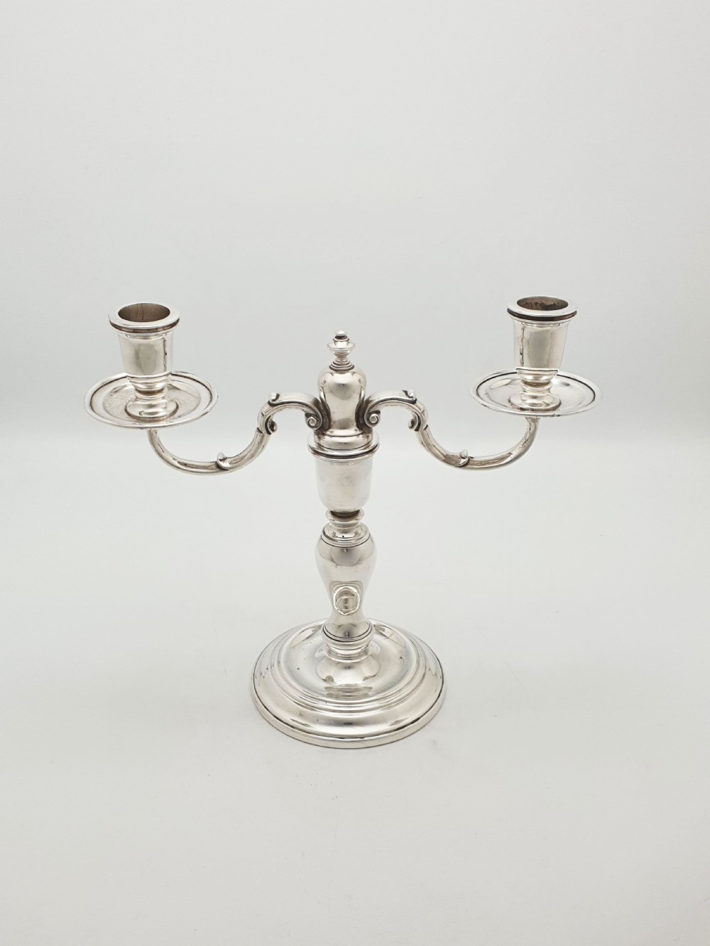 A pair of silver-plated low two-branch candelabra featuring turned central stems, circular stepped bases, and scrolled arms. View V