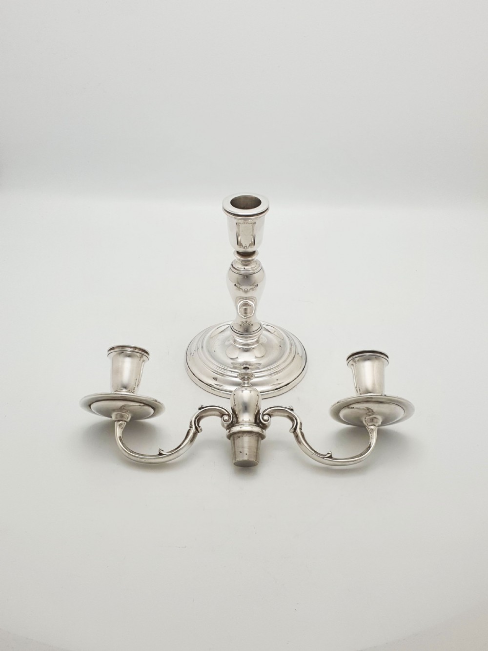 A pair of silver-plated low two-branch candelabra featuring turned central stems, circular stepped bases, and scrolled arms. View VII