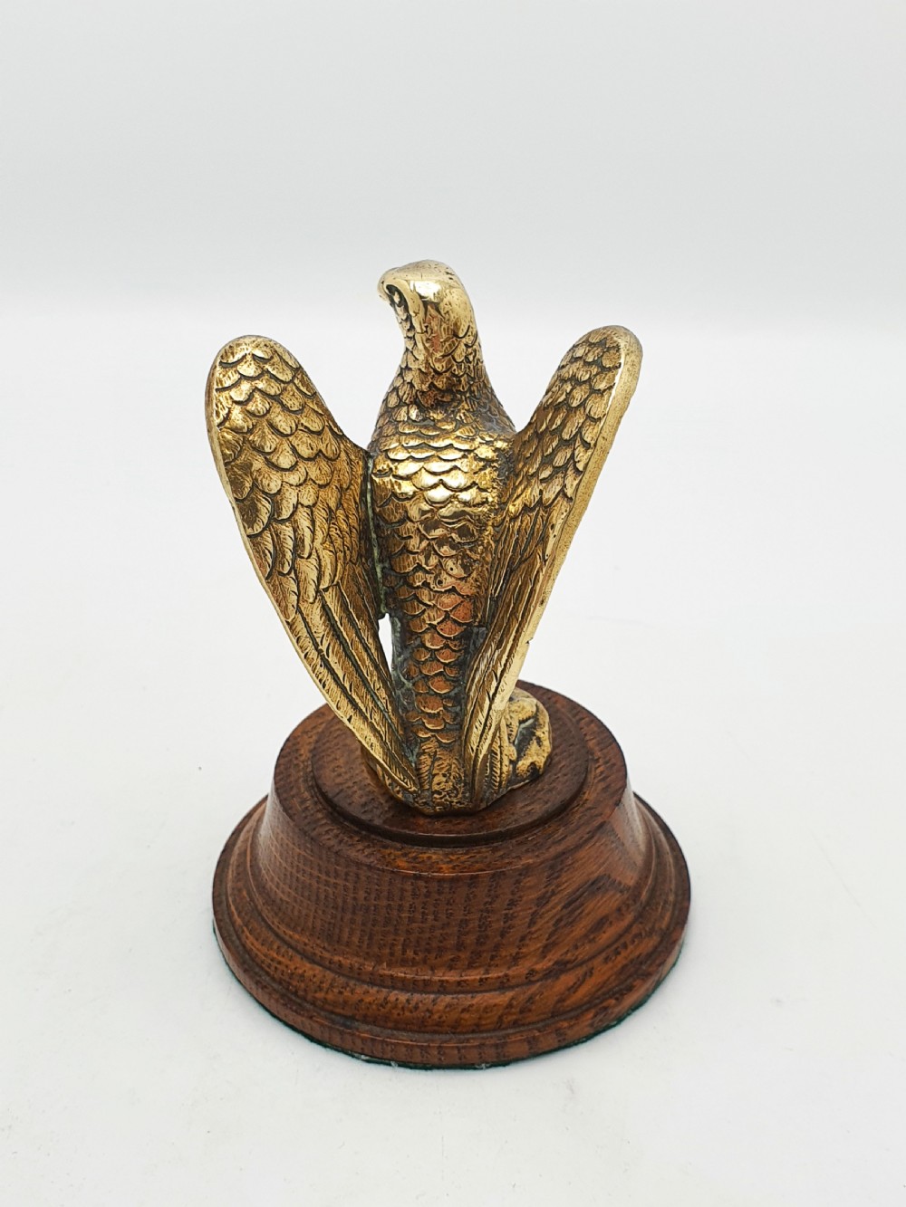 A cast brass eagle figurine with detailed feather engraving, mounted on a stepped circular dark wooden base. View IV