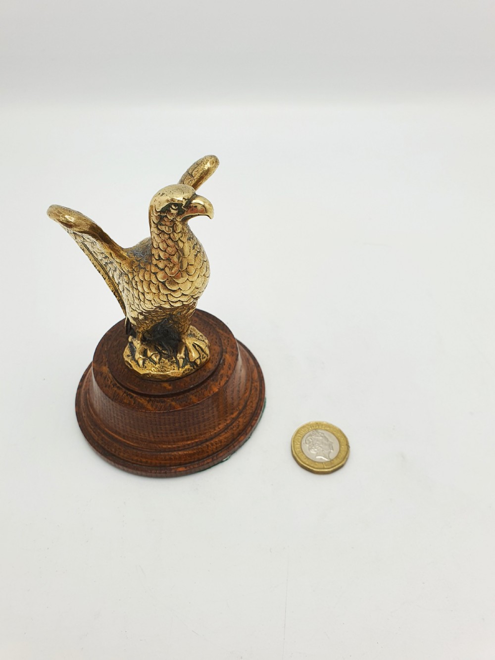 A cast brass eagle figurine with detailed feather engraving, mounted on a stepped circular dark wooden base. View VI
