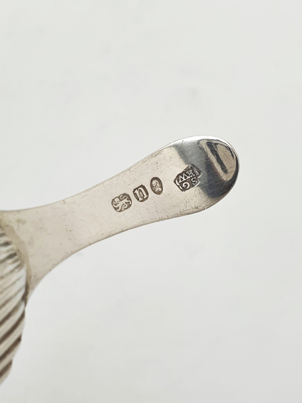 A Georgian sterling silver caddy spoon featuring a fluted shell bowl and an engraved bright-cut handle. View IV